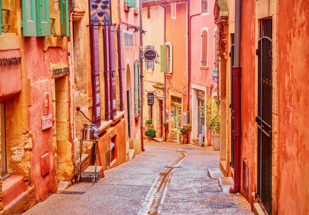  A narrow street in the beautiful French village of Roussillon, where the buildings are made with colorful, locally mined ochre. One of the small frech towns to visit 