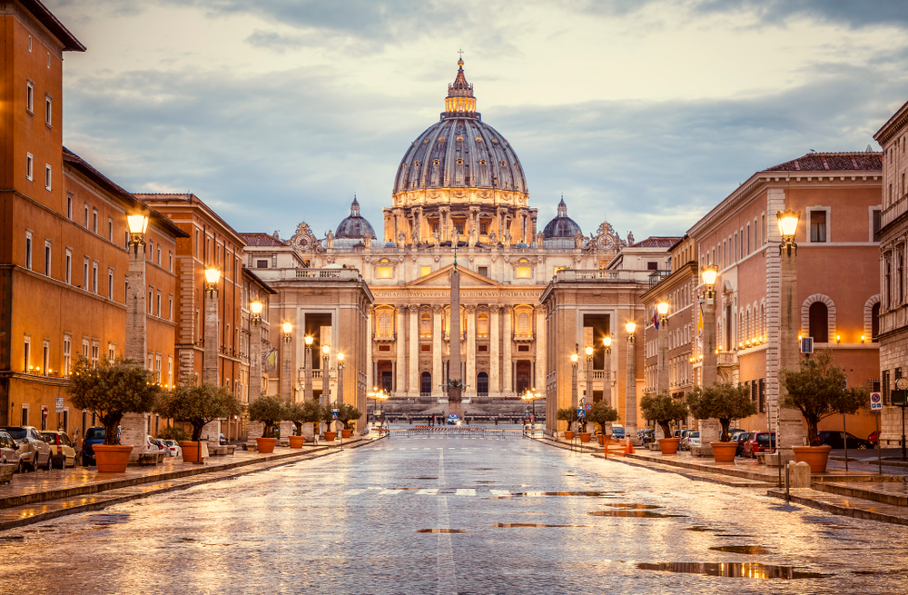 Dusk falls over St. Peter's Basilica in the Vatican City with lamps lit.