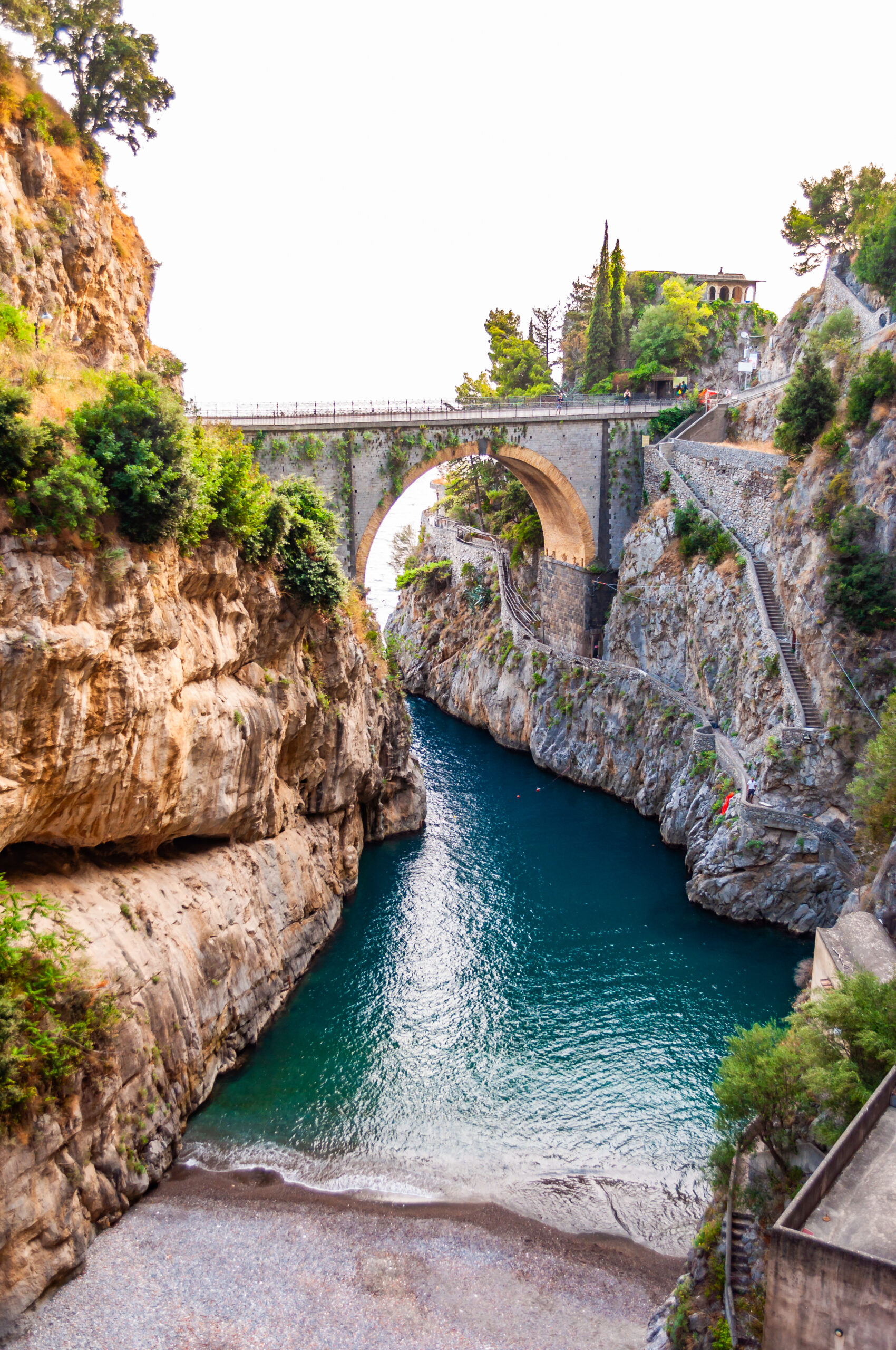 Photo of Furore Beach, one of the more thrilling Amalfi Coast beaches. A stone bridge with cliffs on either side. 