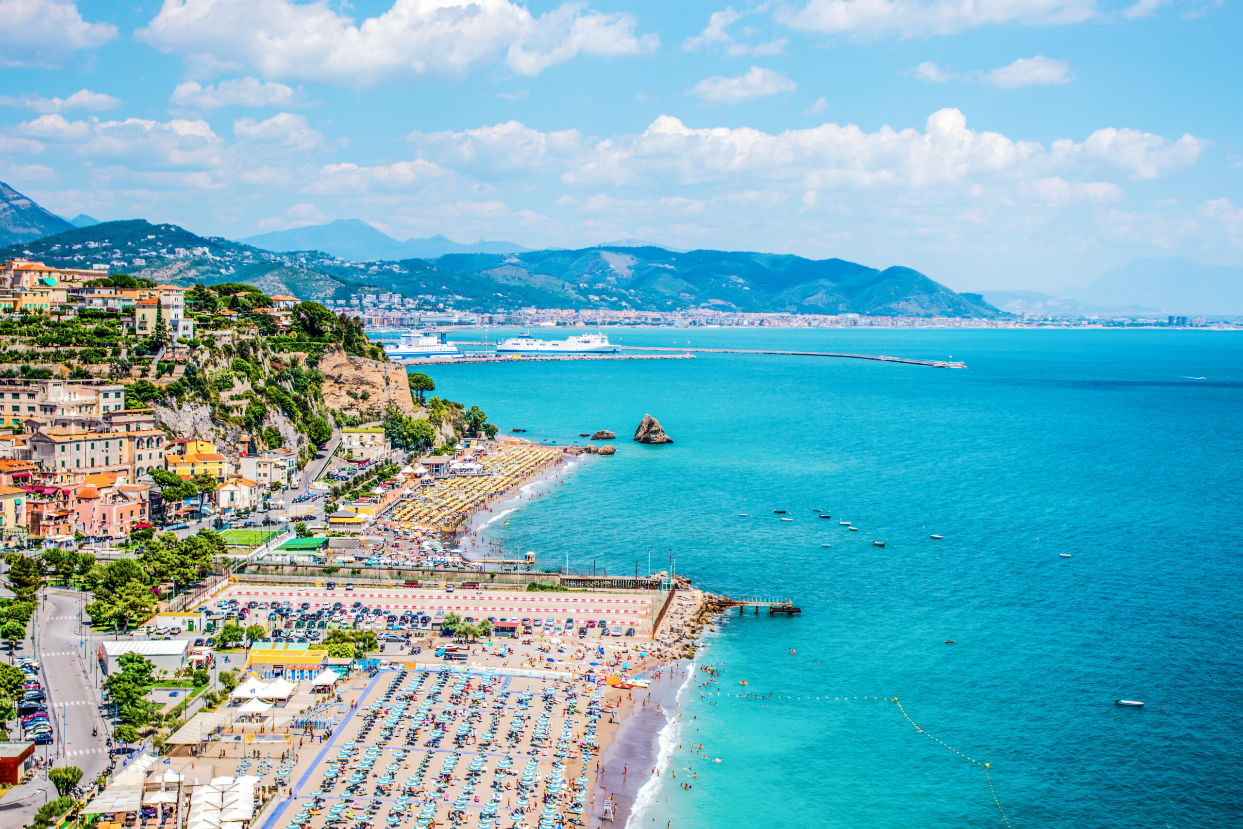 Photo of Vietri sul Mare Beach with umbrellas and chairs. Surrounding buildings can also be seen. 
