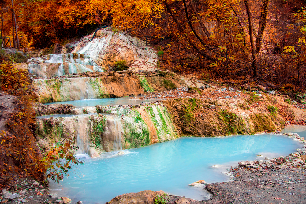 light blue hot spring with red rocks surrounding day trips from Florence