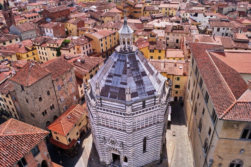 black and white baptistery in Pistoia surrounded by reddish buildings