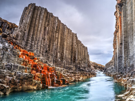 River flowing through the black basalt columns of Studlagil Canyon, one of the hidden gems in Iceland