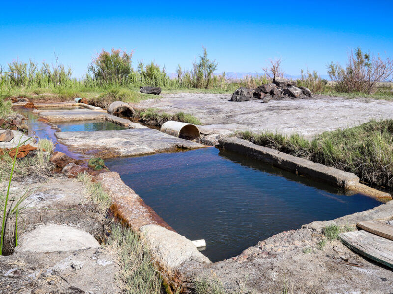 Baker Hot Springs in Utah. Three man made cement pools rest on a grassy plain. 