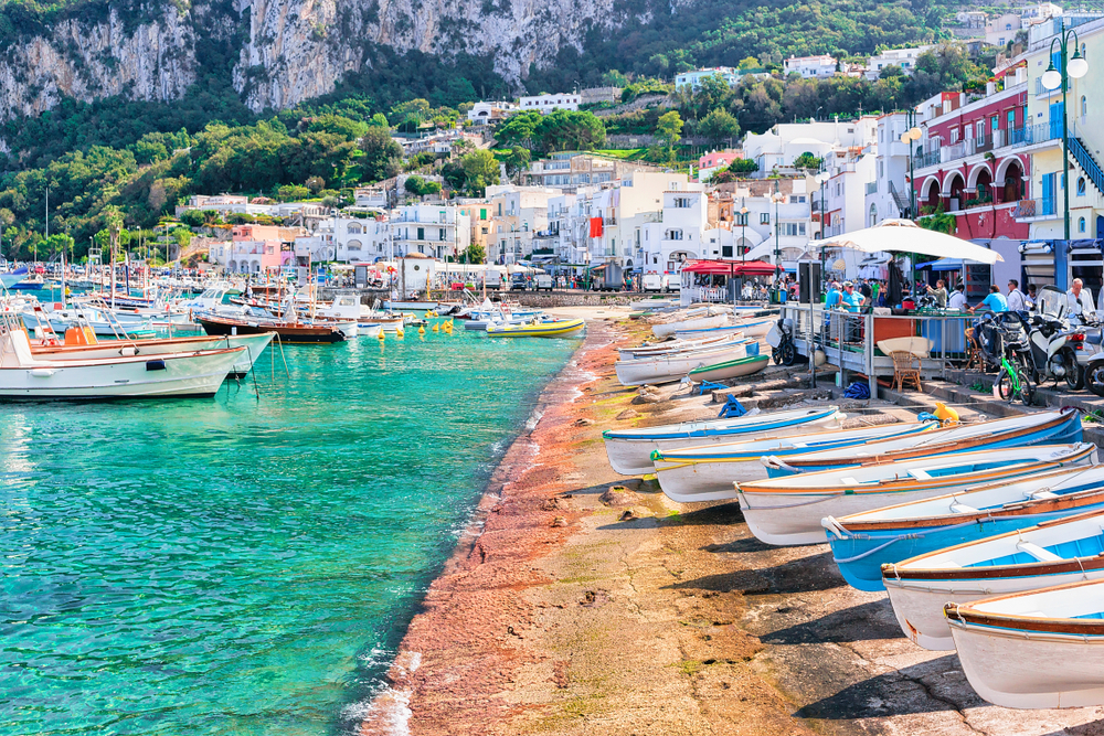 Boats lining the water at the edge of the town in Capri, one of the best beach towns in Italy.