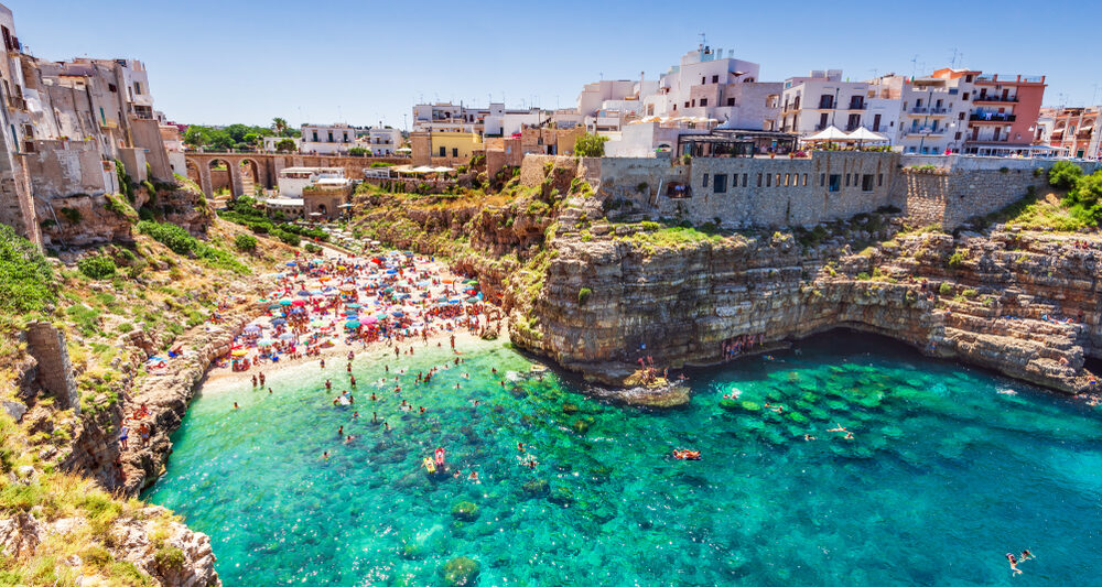 Vibrant turquoise waters leading to a beautiful beach and one of the prettiest beach towns in Italy, Polignano a Mare.