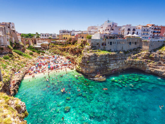 Vibrant turquoise waters leading to a beautiful beach and one of the prettiest beach towns in Italy, Polignano a Mare.