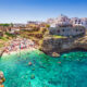 Vibrant turquoise waters leading to a beautiful beach and one of the prettiest beach towns in Italy, Polignano a Mare.