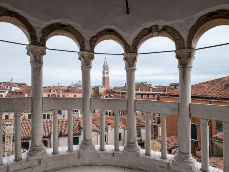 An up high view of Venice from Scala Contarini del Bovolo looking out through arched columns. 