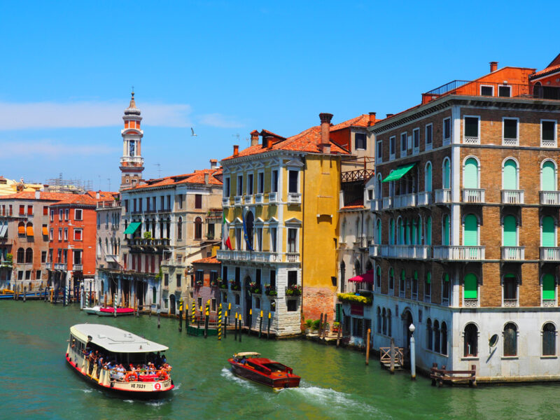A water taxi travels down a large canal in Venice, Italy between colorful buildings.