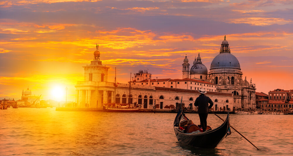 A gondola floats in The Grand Canal at sunset.