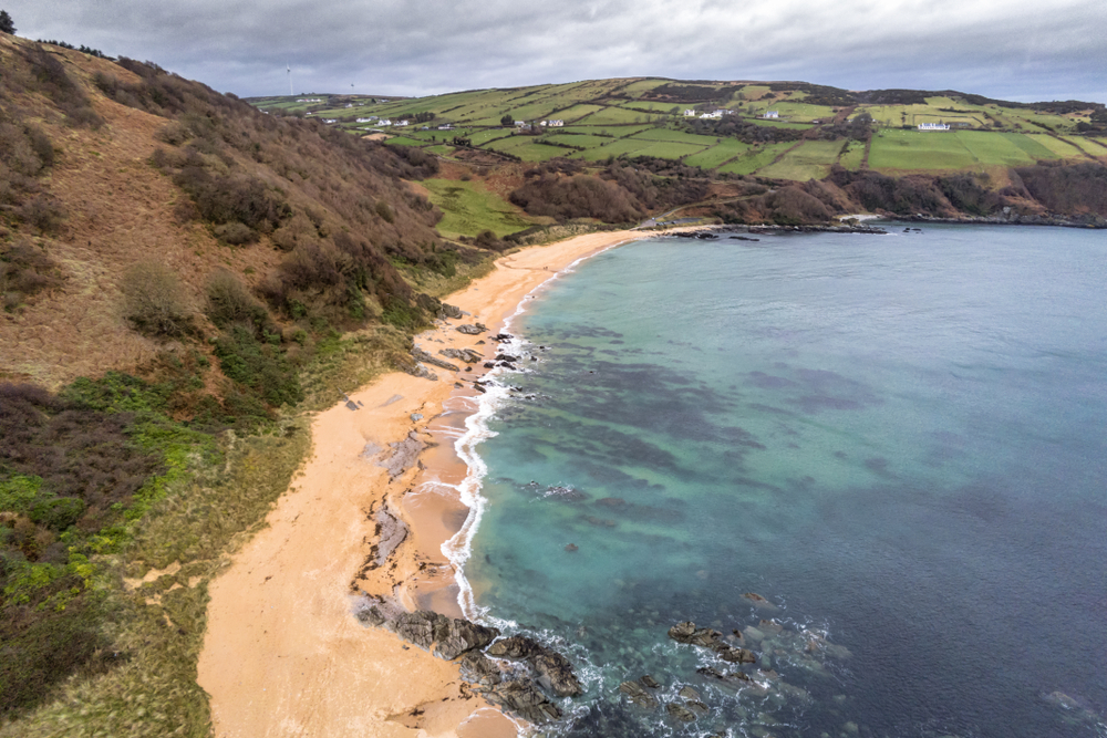 Arial view of Kinnagoe Bay's beautiful turquoise water against the shore. 