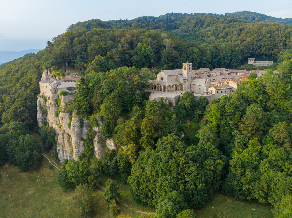 The sanctuary of Verna high on a cliff is one of the things to do in Tuscany. You are see a forested hill with the buildign in between.  