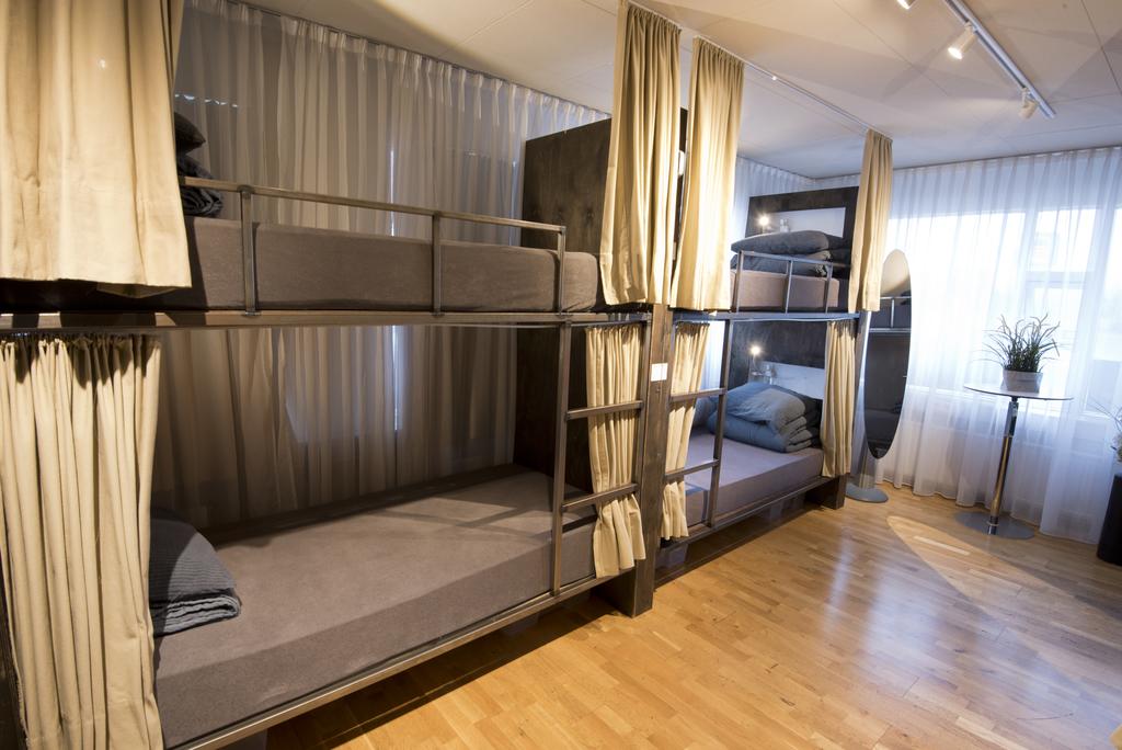 Photo of dorm style accomodations at B14 Hostel located in Reykjavik Iceland. Bunk style beds are seen with ivory curtains. 