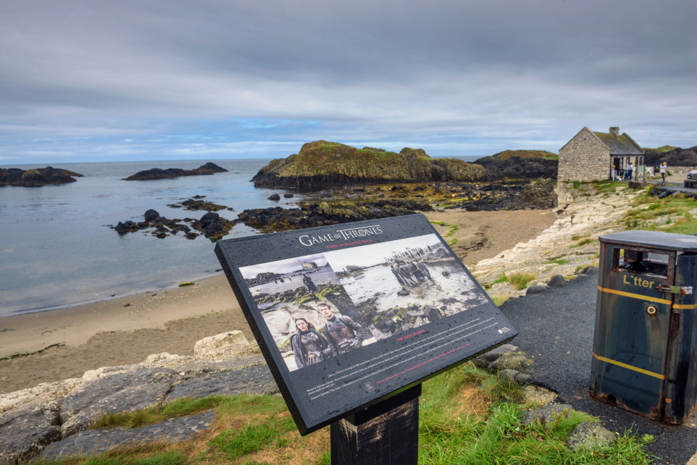 A Game of Thrones Tour is one of the things to do in Northern Ireland for fans. This photo shows a beach in the background with a plaque in the foreground with information about the filming location