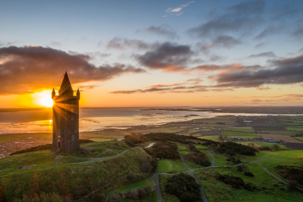 Photo of an orange sunset at Scrabo Tower. The sea is in the background.