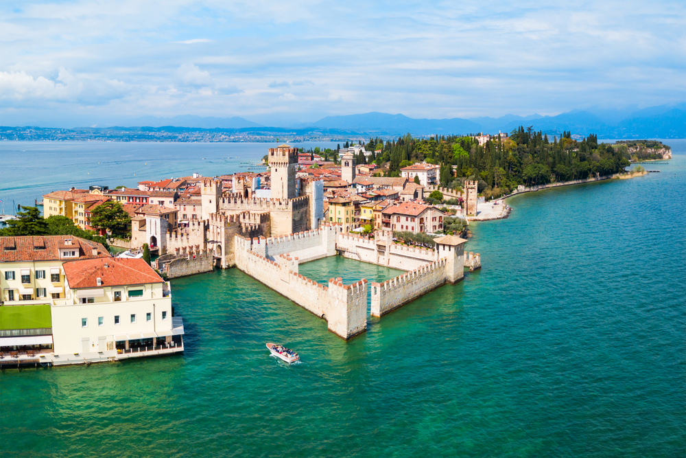 Aerial view of Scaligero Castle with blue water and town around it.