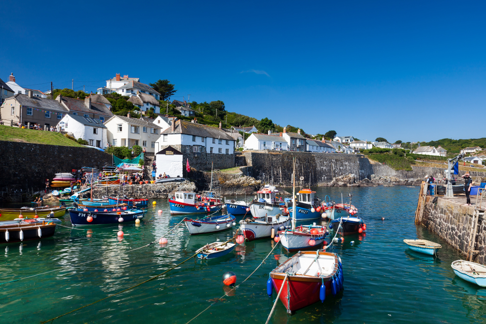 a photo overlooking the bay of Coverack, southern england. The bay is filled with small fishing boats.