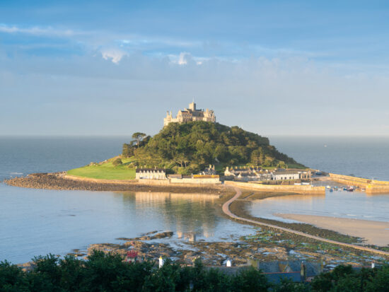 a photo showing St Michael's Mount, a small island with a walkway leading up to it