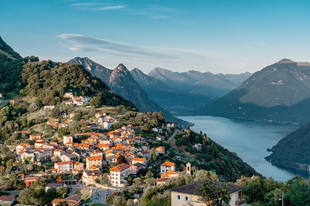 Lugano sits on the edge of Lake Lugano with mountains framing it. one of the most beautiful small towns in Switzerland 