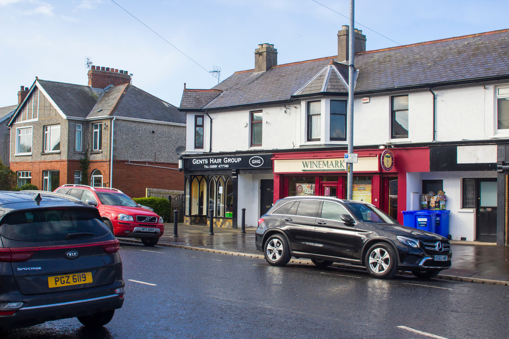 Cars along the side of the road in a small Irish town.