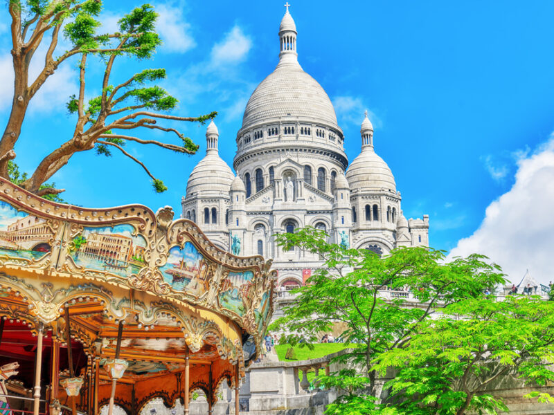 A colorful depiction of Monmarte in Paris with a carousel and cathedral. 