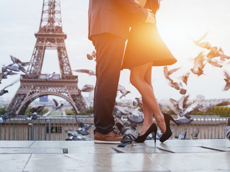 Azoom in shot of two lovers embracing in front of the Eiffel Tower in Paris at sunset. 