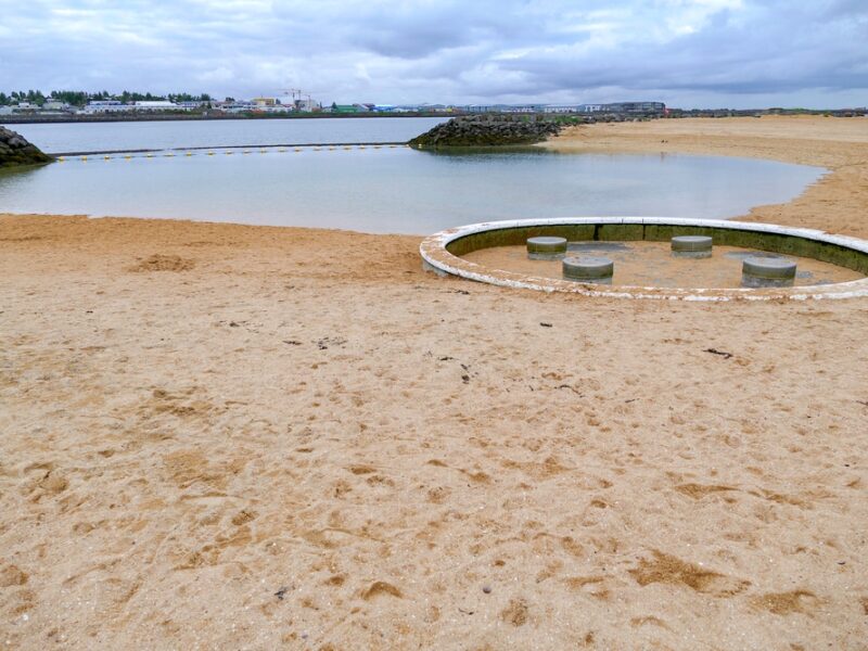 Nautholsvik Beach with a glimpse of the ocean and Reykjavik. 