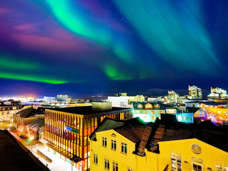 The streets of Reykjavik lit by purple, green and blue Northern Lights.