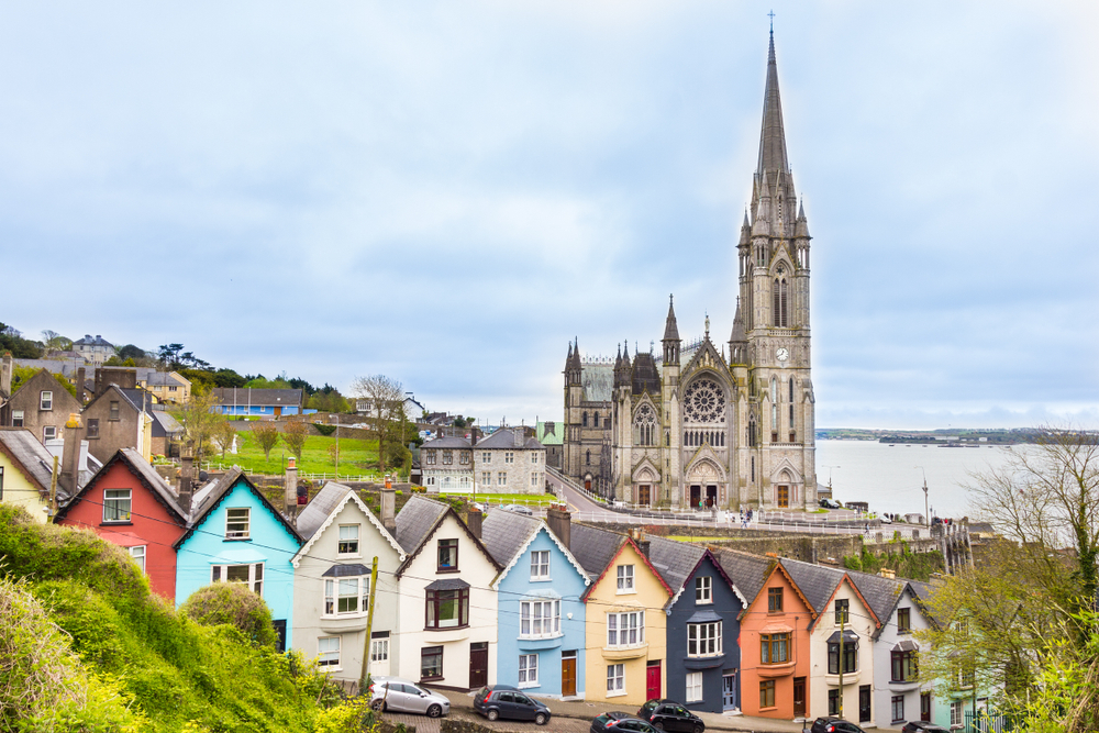 Line of colorful houses with a cathedral in the background in Cobh, Ireland.