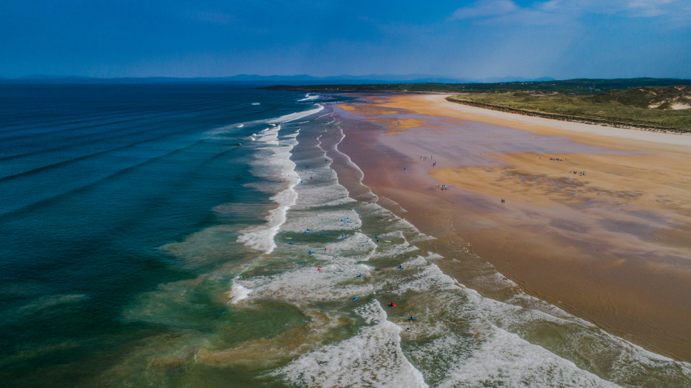 Aerial view of people surfing at Donegal Beach in Ireland.