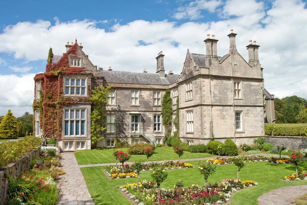 Exterior of Muckross House with ivy and a pretty garden.