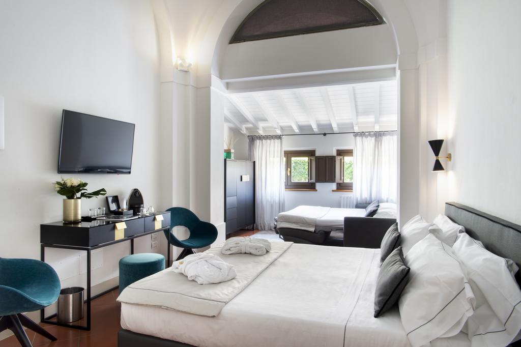 Photo of guest room at Horto Convento in Florence. Very stylish room with modern decor. Mostly white with pops of teal, gray, and gold.
