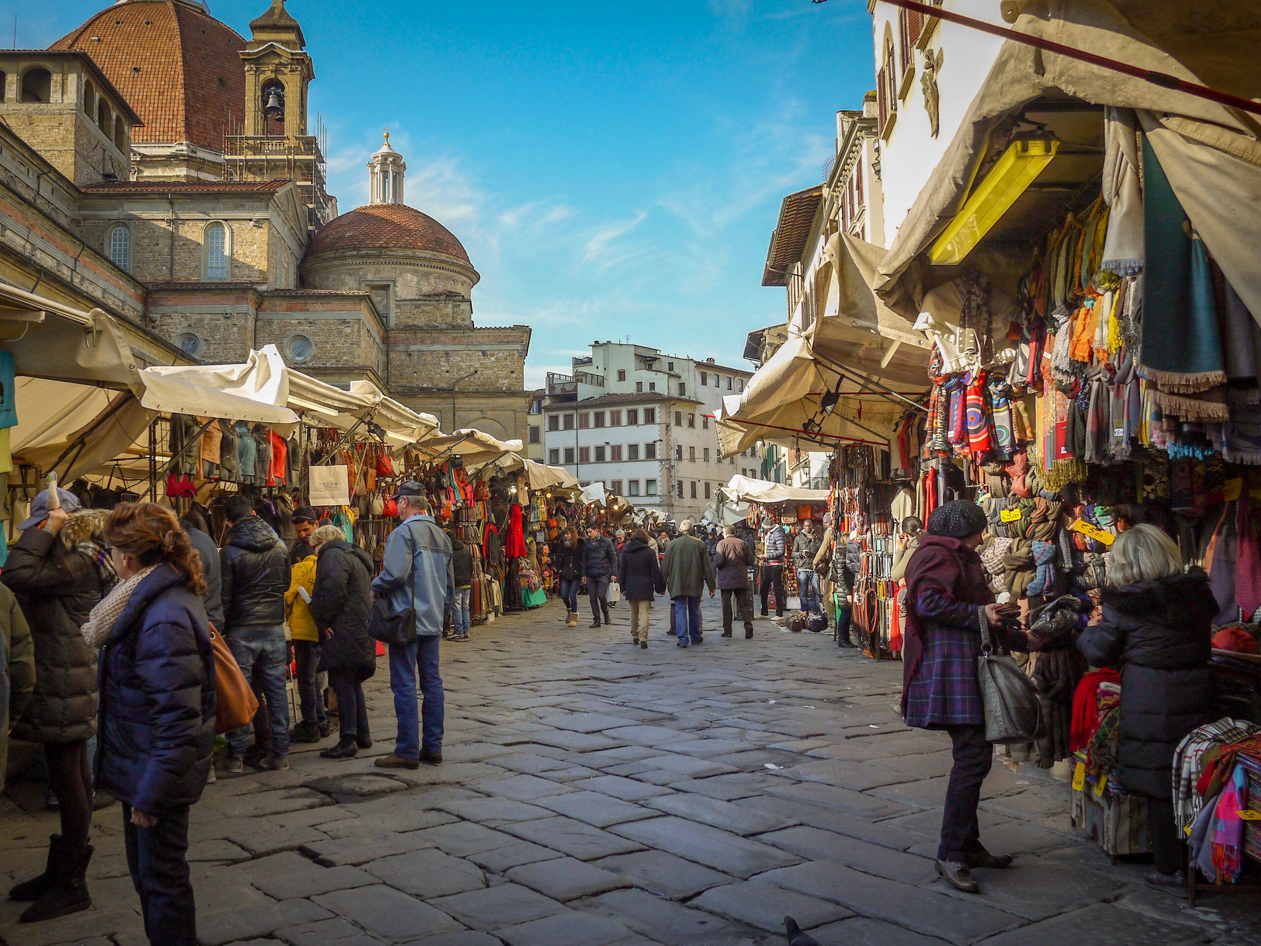 The outdoor area of the San Lorenzo markets full of stalls selling leather, clothing, and souvenirs to tourists.