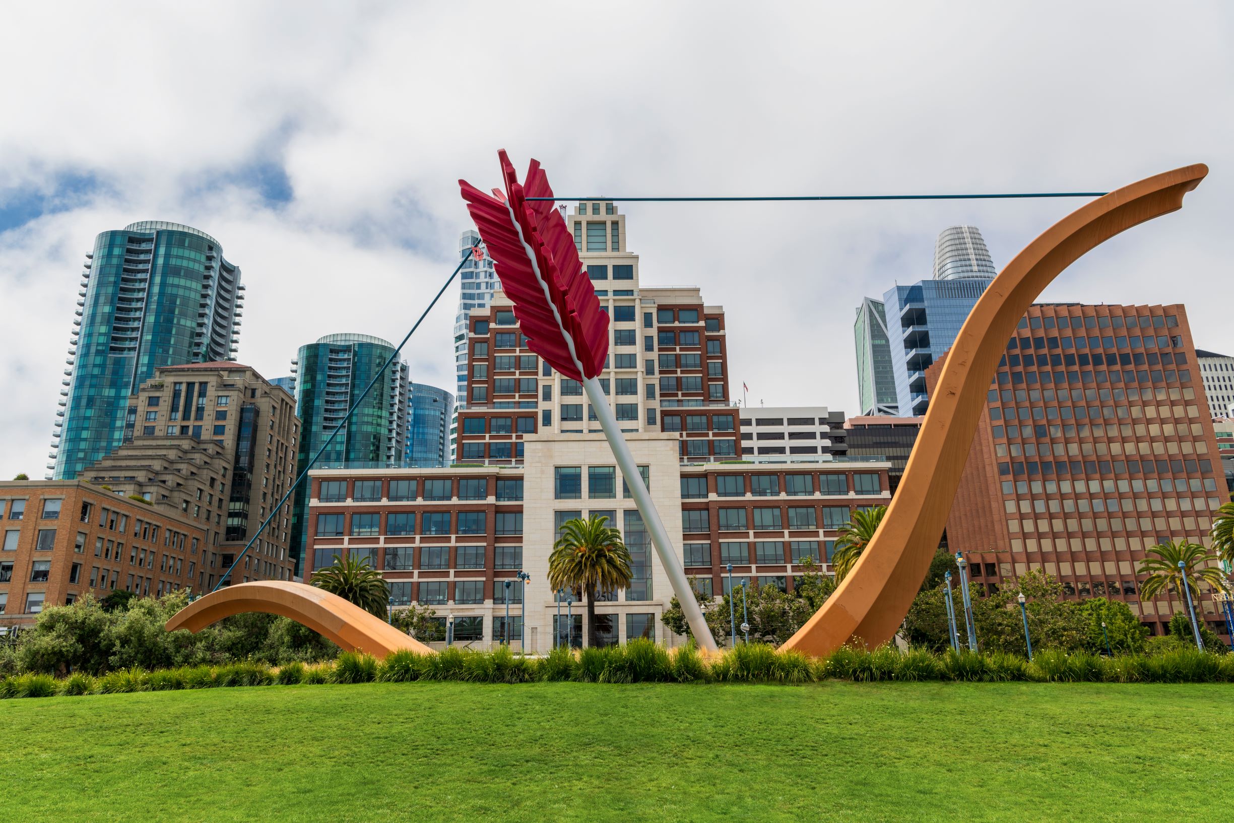 Photo of Cupid's Span in San Francisco's Financial District, the best place to stay in San Francisco for luxury hotels. Photo shows a large bow and arrow sculpture with the city skyline behind it. 