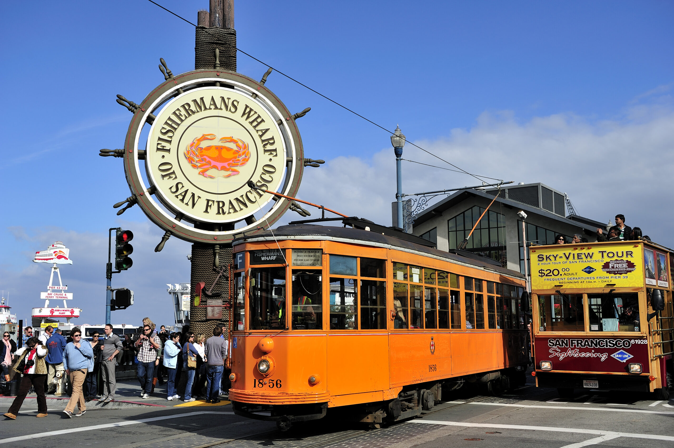 Photo of Fisherman's Wharf, one of the best places to stay in San Francisco. Photos features iconic Fisherman's Wharf sign with two cable car along the sidewalk. 