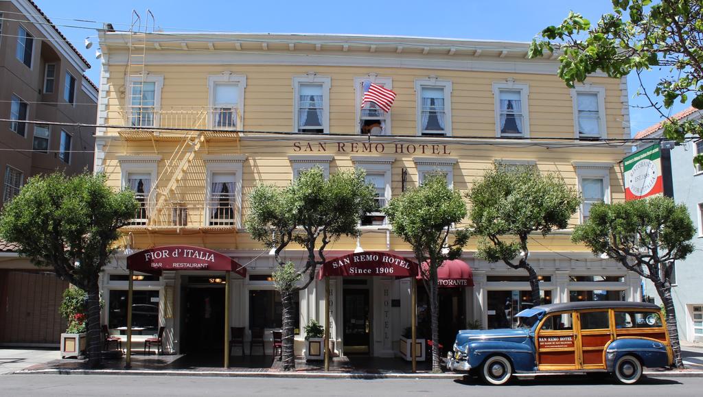 Photo of the front of San Remo Hotel in San Francisco. Features a pale yellow building with maroon awnings. 