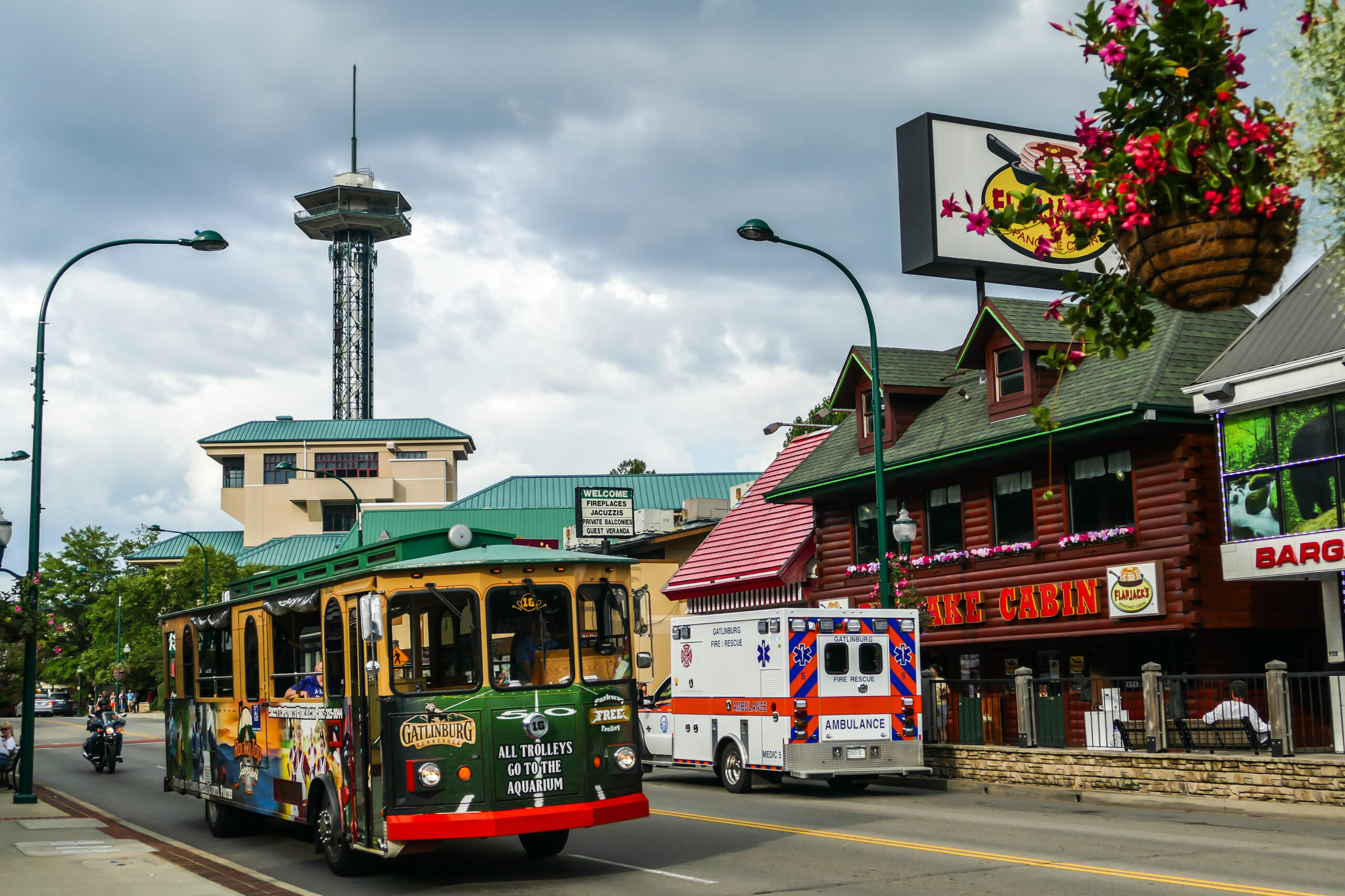 Photo of the Gatlinburg Trolley with the Gatlinburg Space Needle seen in the background. One of the fun free things to do in Gatlinburg.