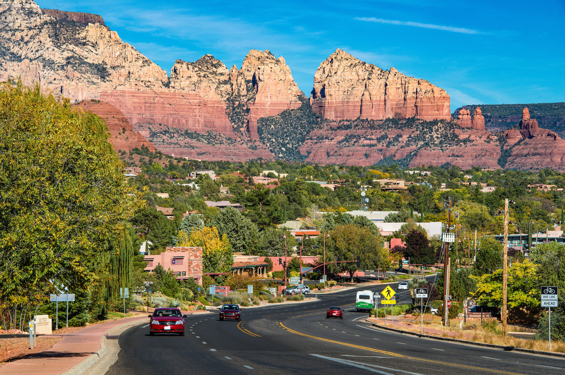 cars on road with red rocks towering in the background