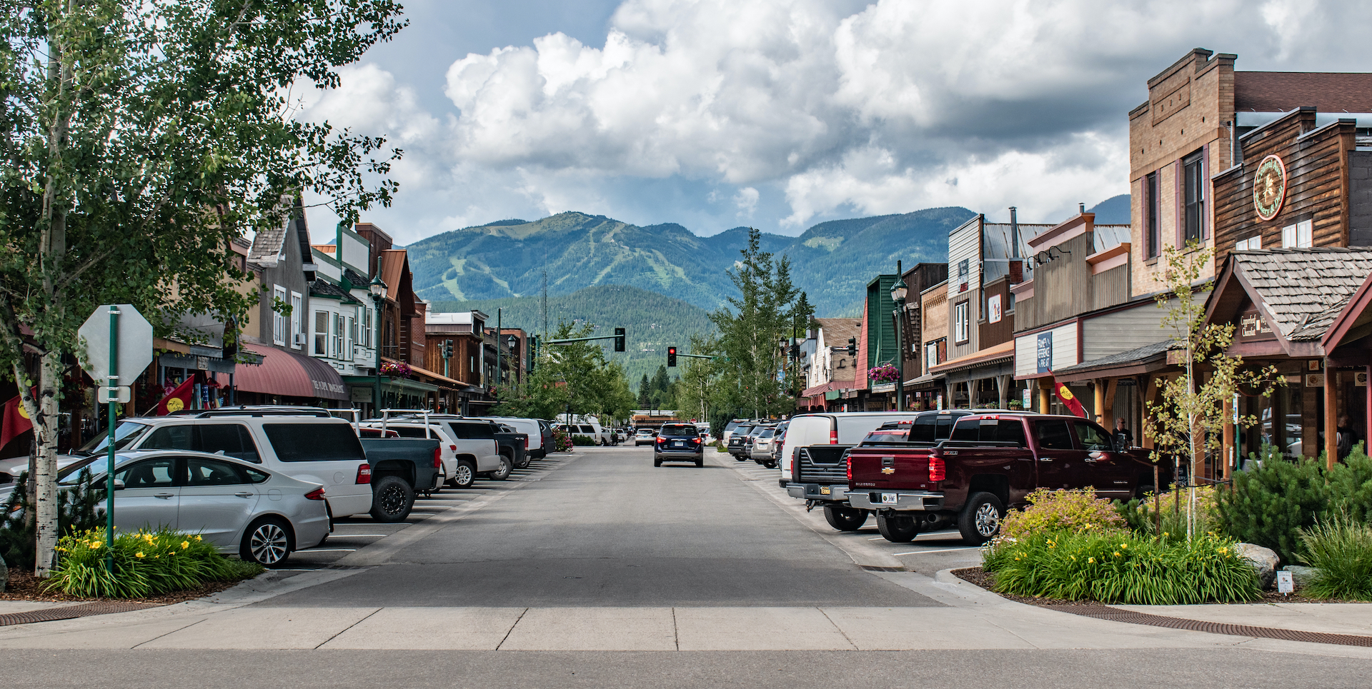 cars lining old-timey street with green mountains in the background