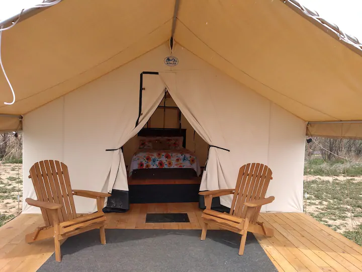 A glamping tent with two chairs outside 