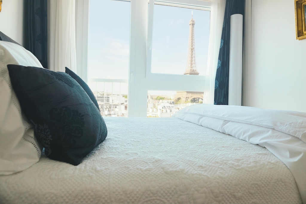 view of a luxurious bed with the eiffel tower visible from the window