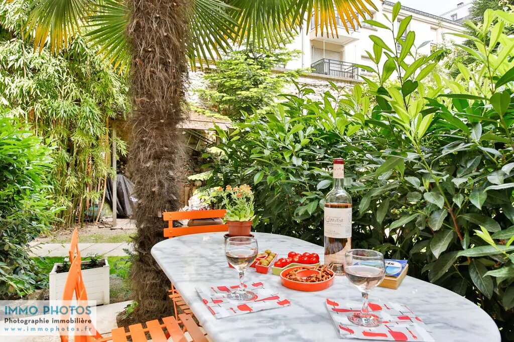 view of a beautiful table set with wine and snacks in the lush private garden of this paris apartment