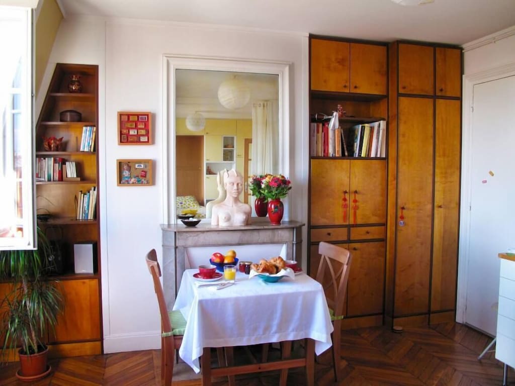 view of the built in bookshelves and a breakfast table laden with a french feast 