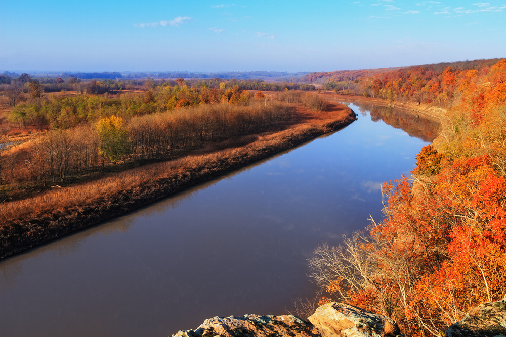 wide river lined with orange and red trees fall in the USA