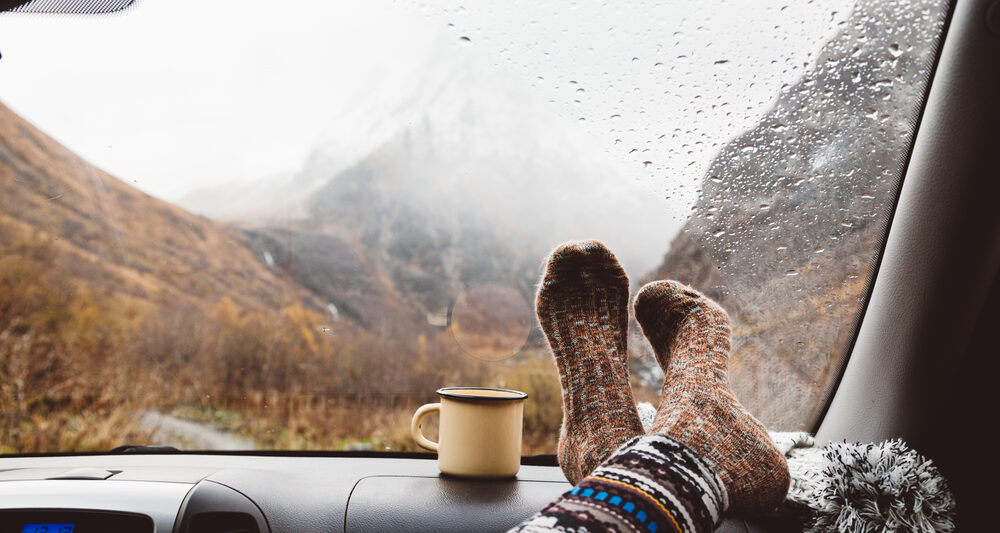 A passenger puts her socks up on the dashboard while it rains