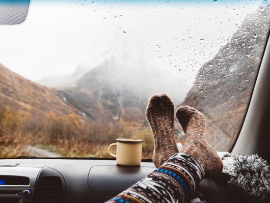 A passenger puts her socks up on the dashboard while it rains