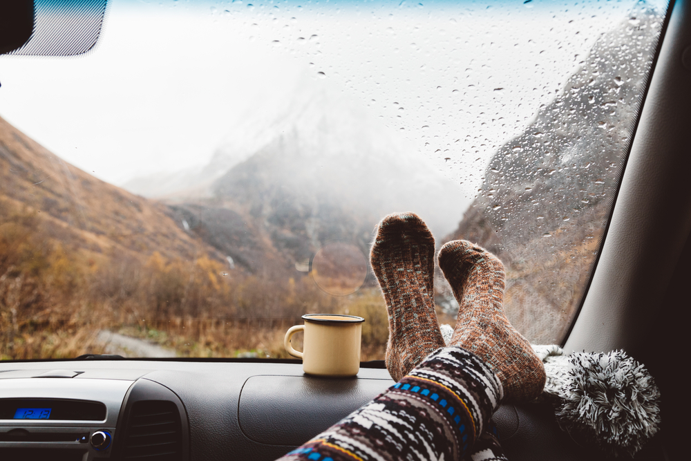 A passenger puts her socks up on the dashboard while it rains