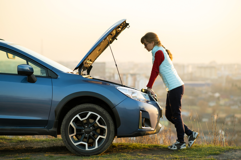 A woman looks over the hood of her car