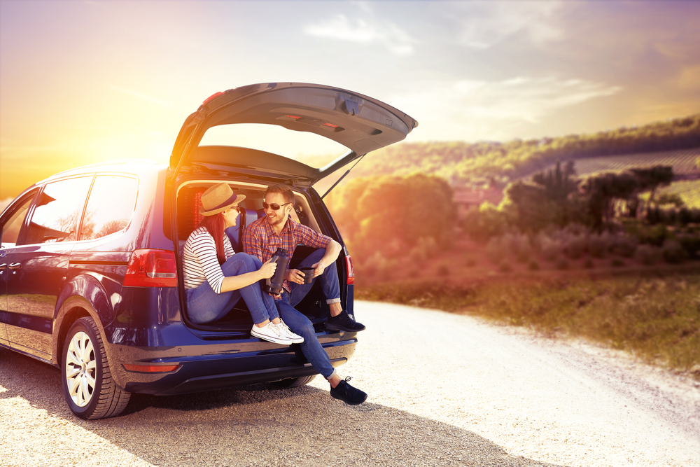 a couple sits in the back of their car during a trip